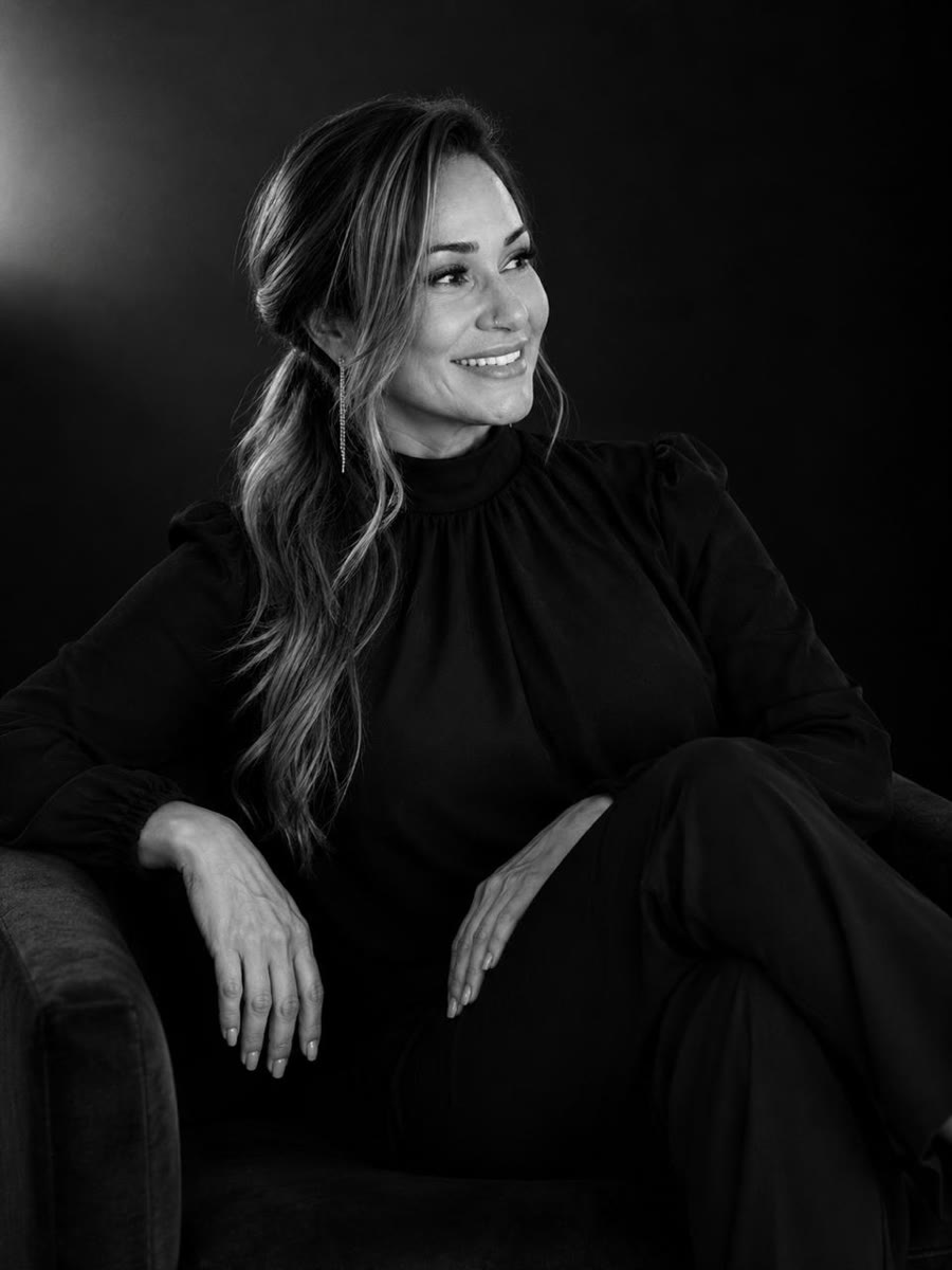 Miriam Nery sentada, em look preto e branco, durante ensaio de estúdio